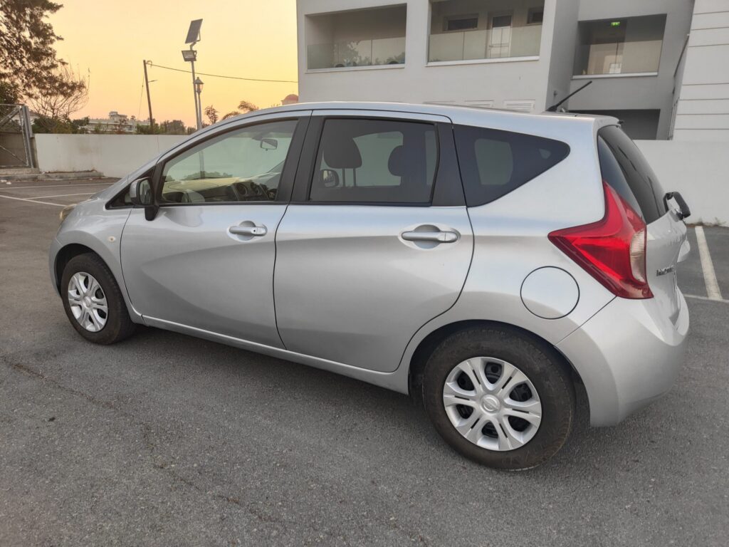 Silver Nissan Note 5-door hatchback hire car, rear three-quarter view, Cyprus