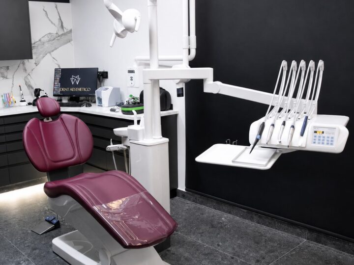 Modern dental treatment room in Larnaca with a burgundy dental chair, overhead light and digital instrument console